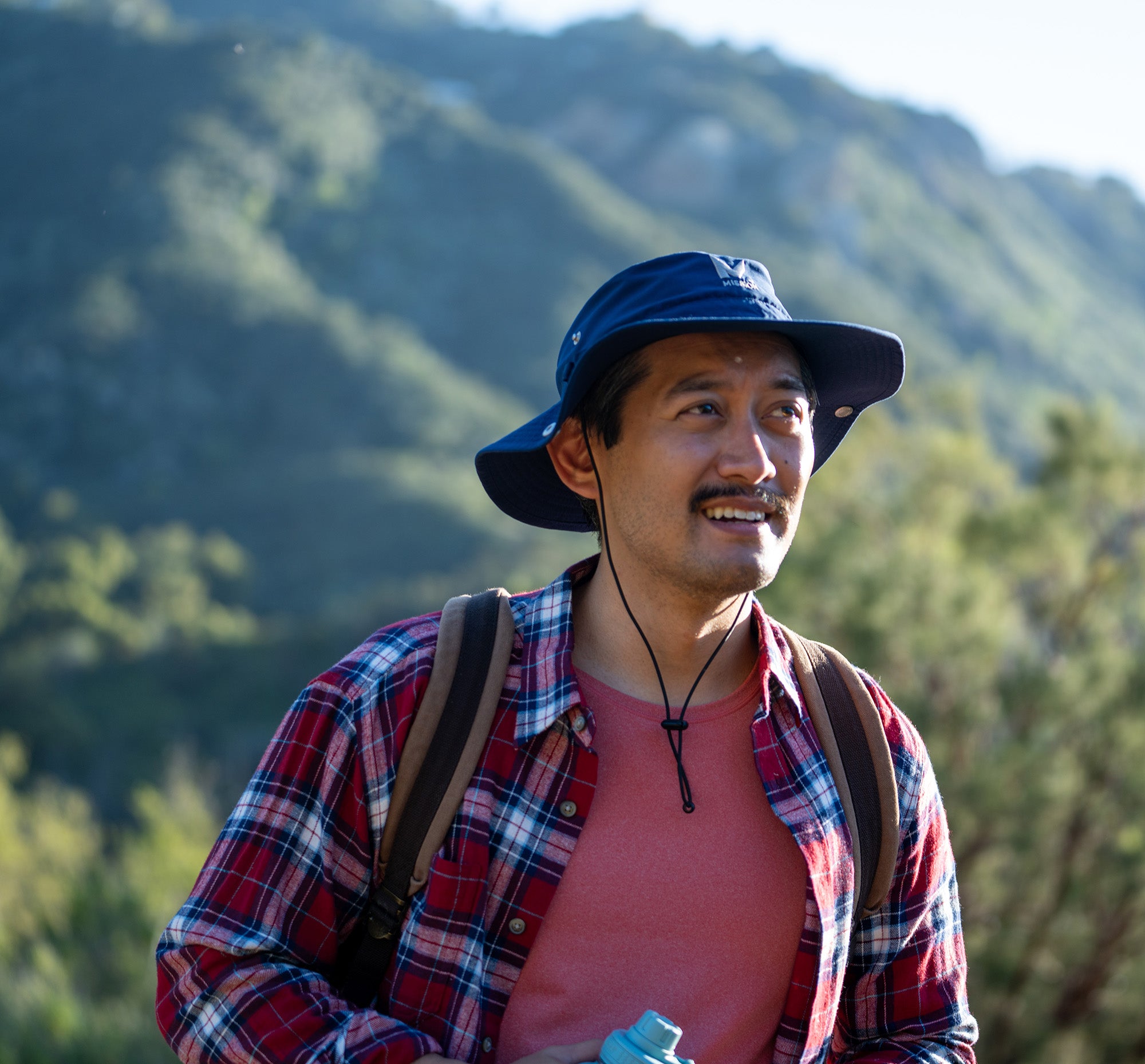 man in a cooling bucket hat against the background of mountains