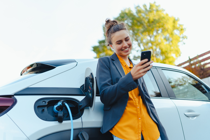 Young woman at an EV Charging Installation in Sydney - using smartphone to operate EV Charger