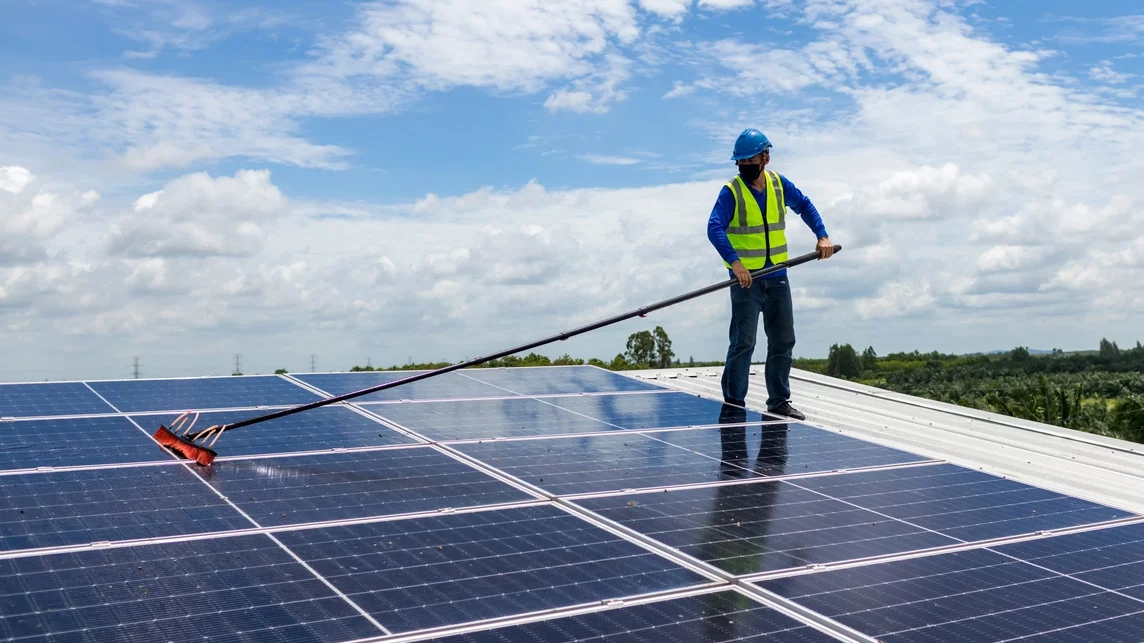 Worker on the roof cleaning solar panels